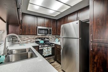 Renovated kitchen with espresso cabinets, white countertops and stainless steel appliances